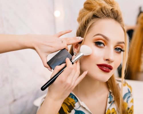 Preparing to party, carnival, celebration of attractive young women in beauty salon. Making makeup, stylish coiffure, professional stylist, cheerful mood, fashionable model