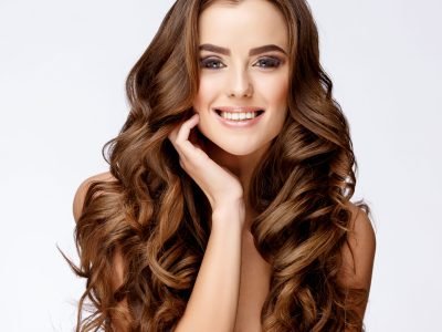 Beautiful Face of Young Woman with Clean Fresh Skin close up on light grey background. Beauty Portrait. Beautiful Woman Smiling. Perfect Fresh Skin. Pure Beauty Model. Youth and Skin Care Concept