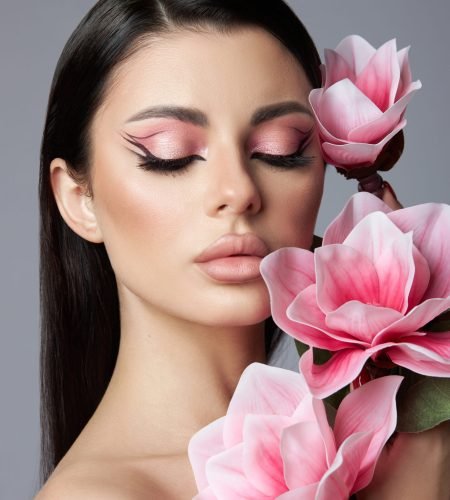 Beauty portrait of a woman, pink eye shadow makeup, arrows and long eyelashes. Brunette woman, red nail polish, natural cosmetics