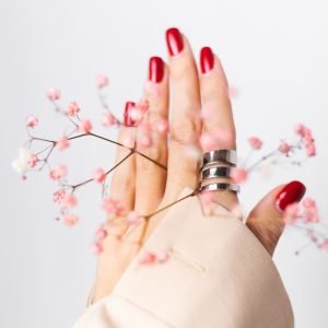 soft-gentle-photo-woman-hand-with-big-ring-red-manicure-hold-cute-little-pink-dried-flowers-white